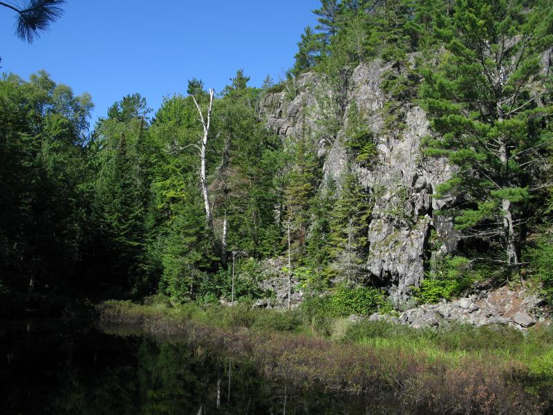 Towering rock bluff over a small, stagnant pool